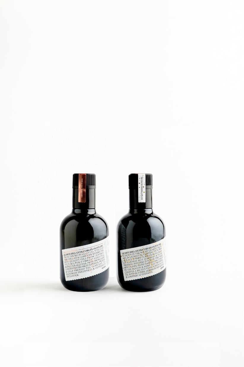 Two dark glass bottles of olive oil, one labeled 'Estate' and the other labeled 'Alluvial Press', set against a white background. 250ml format to try best of both olive oil.