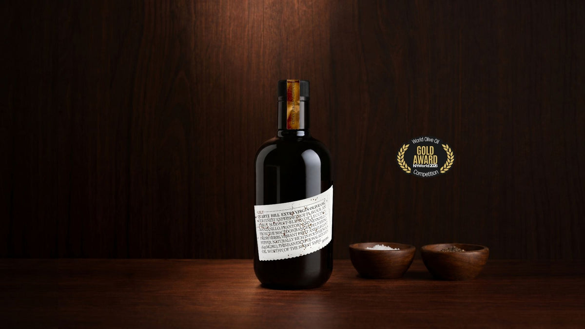 australian made EVOO in a black glass bottle next to its award for best olive oil in the world competition.
